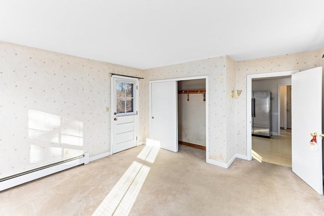 unfurnished bedroom featuring a closet, light colored carpet, stainless steel refrigerator, and a baseboard radiator