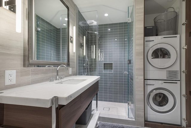 bathroom with stacked washer and clothes dryer, a stall shower, tile walls, vanity, and backsplash