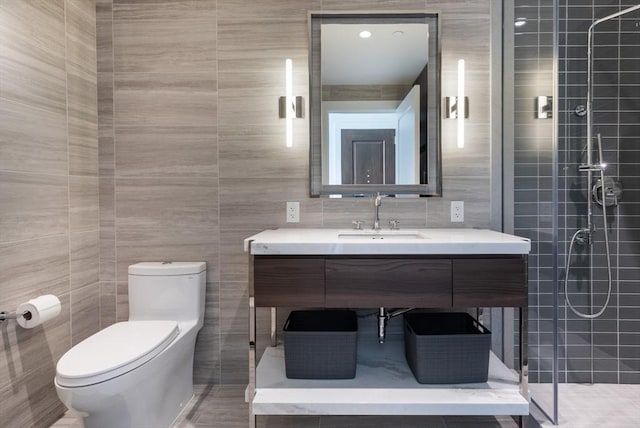 bathroom featuring tile walls, tiled shower, toilet, and vanity