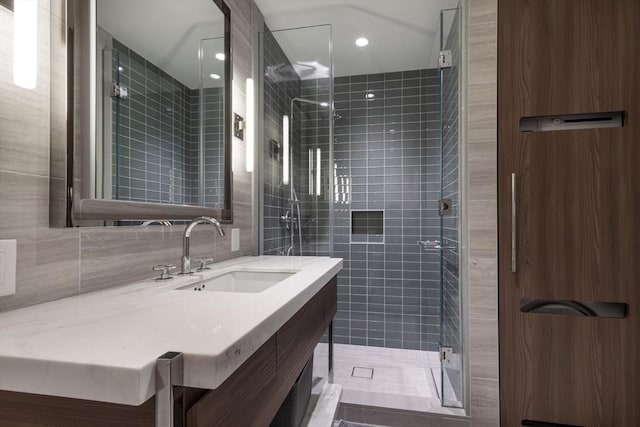bathroom featuring a shower stall, tile walls, and vanity