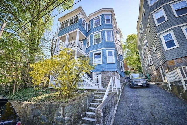 victorian house featuring stairs, aphalt driveway, and a balcony