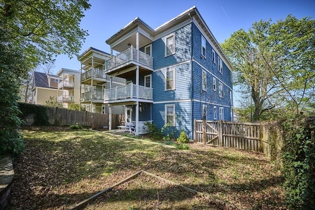 back of property featuring a fenced backyard and a balcony