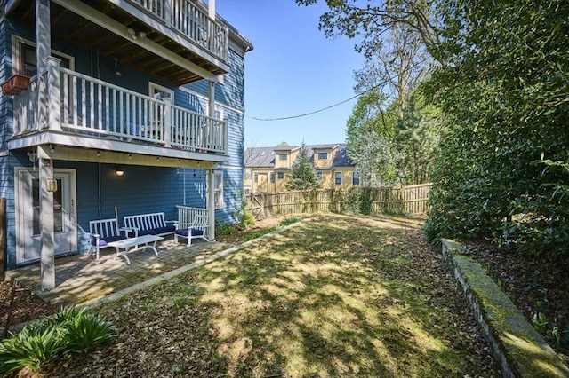 view of yard featuring fence, a patio, and a balcony
