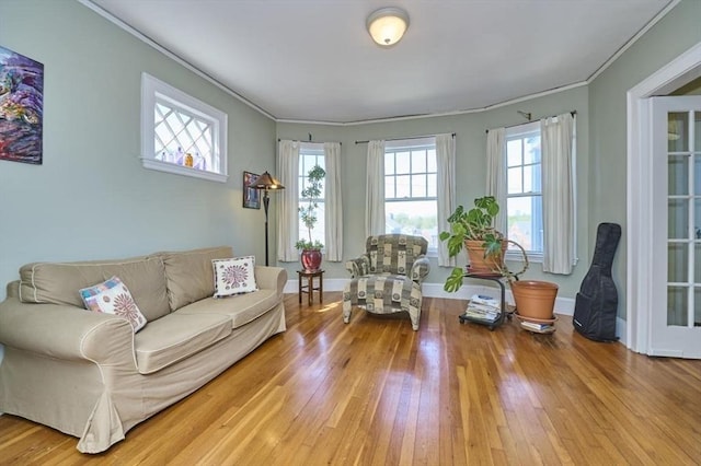 living area featuring crown molding, baseboards, and wood finished floors
