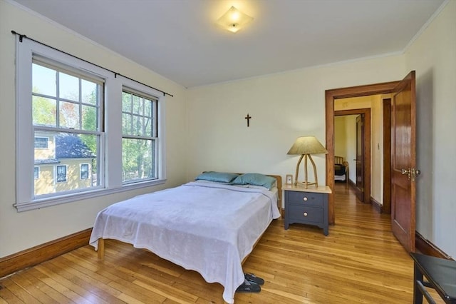bedroom with baseboards, ornamental molding, and light wood finished floors