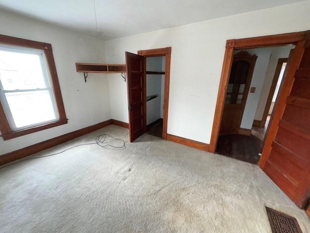 unfurnished bedroom with a closet, visible vents, light carpet, and baseboards