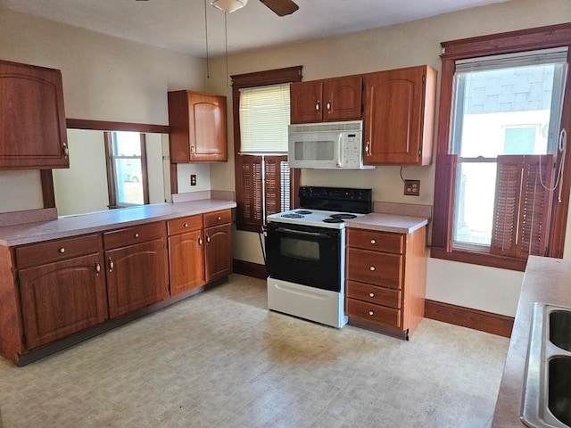 kitchen with baseboards, range with electric cooktop, white microwave, brown cabinets, and light countertops