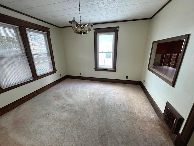 empty room featuring crown molding, a notable chandelier, visible vents, carpet flooring, and baseboards