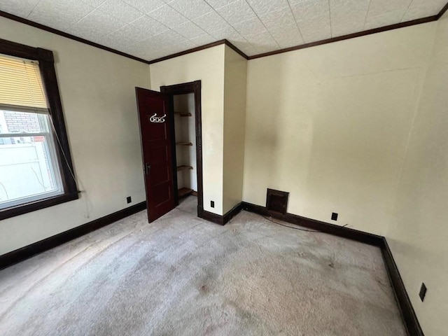 empty room with visible vents, ornamental molding, light colored carpet, and baseboards