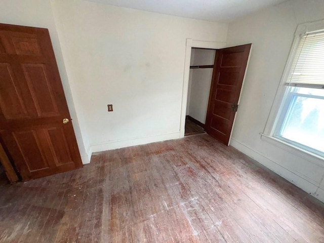 unfurnished bedroom with a closet, wood-type flooring, and baseboards