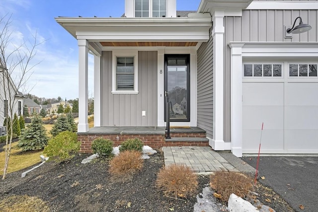 view of exterior entry with board and batten siding and a garage