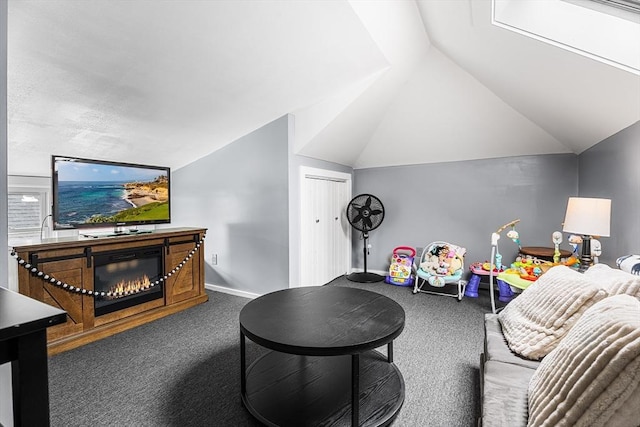 carpeted living room featuring lofted ceiling, baseboards, and a glass covered fireplace