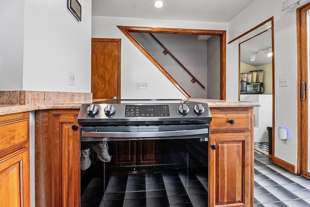 kitchen view of stainless steel electric range oven and brown cabinetry