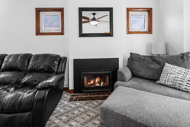 living area with a ceiling fan and a fireplace