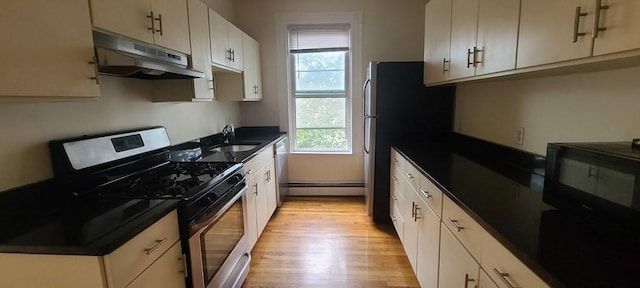 kitchen featuring a wealth of natural light, stainless steel appliances, a baseboard heating unit, and light wood-type flooring