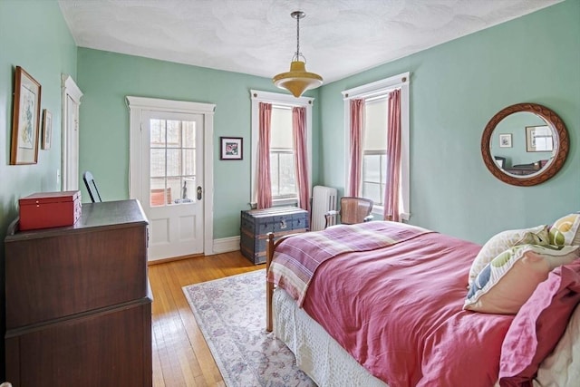 bedroom with radiator heating unit and light wood-type flooring