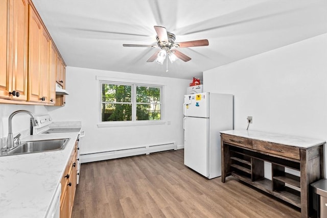 kitchen featuring freestanding refrigerator, a baseboard heating unit, a sink, under cabinet range hood, and wood finished floors