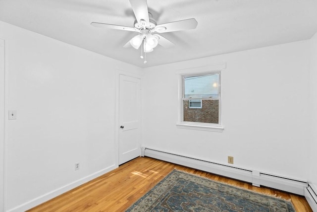 spare room featuring baseboards, ceiling fan, light wood-style flooring, and baseboard heating