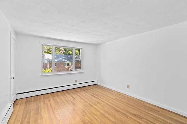 spare room featuring a baseboard radiator, baseboard heating, a textured ceiling, wood finished floors, and baseboards