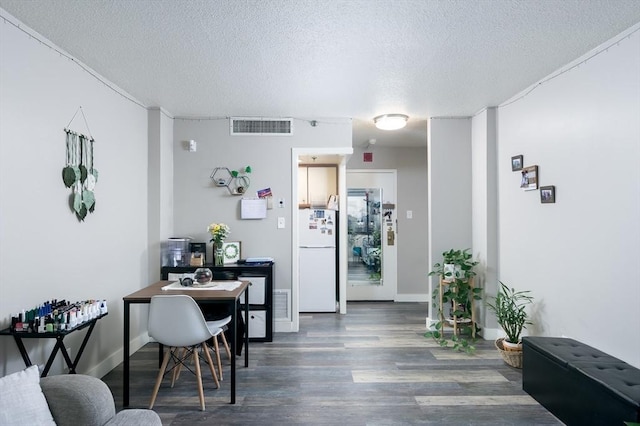 office area featuring a textured ceiling, dark wood-type flooring, visible vents, and baseboards