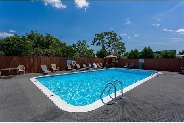 pool with a patio area and fence