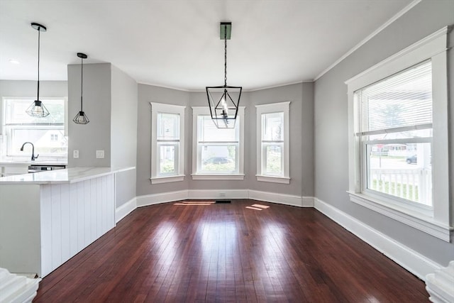 unfurnished dining area with dark wood finished floors, baseboards, and crown molding