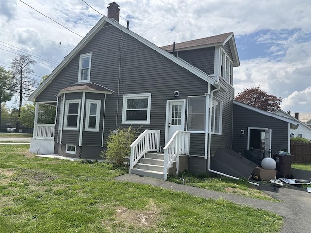 rear view of property with a chimney and a yard
