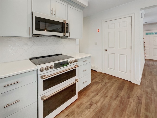 kitchen with high end range, tasteful backsplash, and hardwood / wood-style flooring