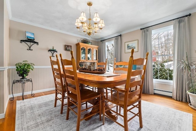 dining area featuring light wood-style floors, a wainscoted wall, crown molding, and baseboard heating