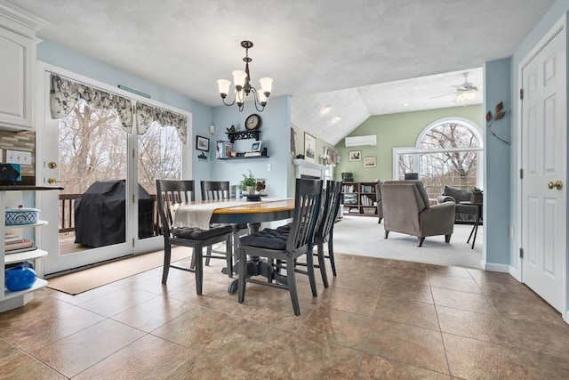 dining room featuring lofted ceiling, a wall unit AC, a fireplace, and an inviting chandelier