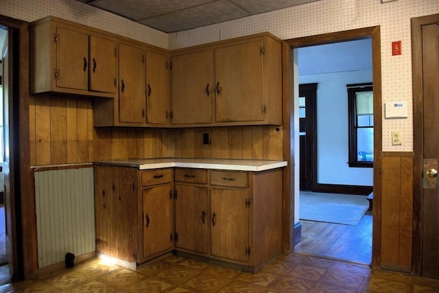 142 College St, Worcester, MA 01610 - kitchen featuring wallpapered walls, parquet floors, light countertops, and brown cabinetry