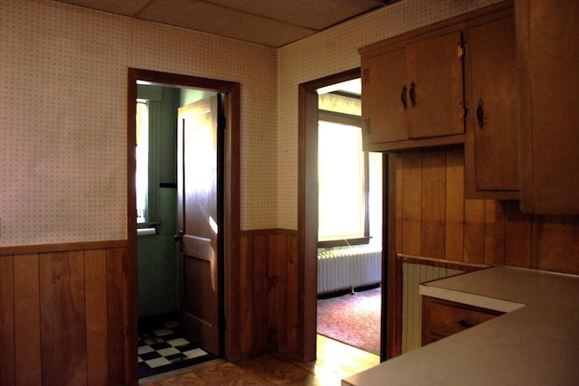 142 College St, Worcester, MA 01610 - kitchen with radiator heating unit, wallpapered walls, a wainscoted wall, brown cabinets, and light countertops