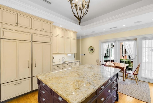 26 Winter St, Salem, MA 01970 - kitchen with cream cabinetry, light wood-style flooring, a chandelier, crown molding, and light stone countertops