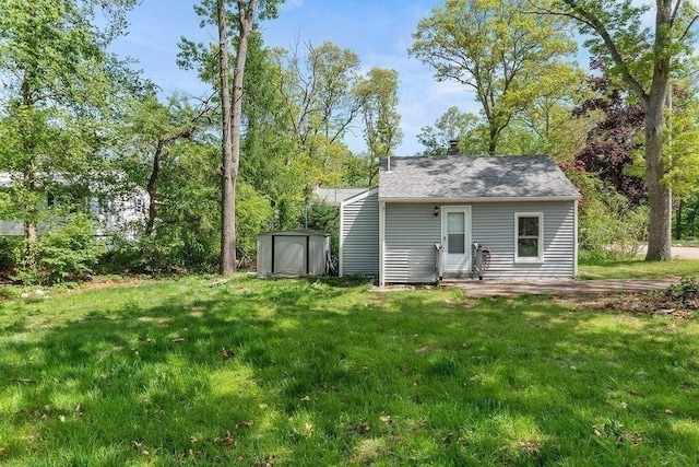 rear view of house with an outdoor structure, a yard, and a storage shed