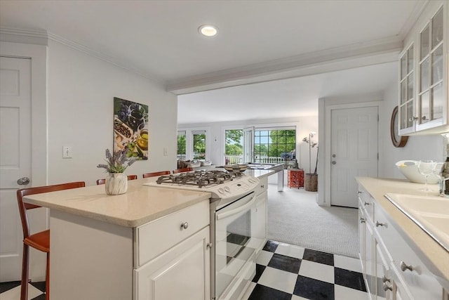 117 Parker Rd, Barnstable, MA 02655 - kitchen with white range with gas stovetop, light countertops, a breakfast bar area, glass insert cabinets, and a center island