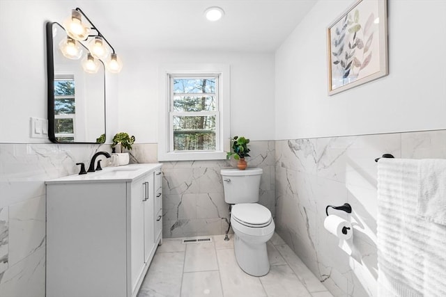 bathroom featuring vanity, tile walls, tile patterned floors, and toilet