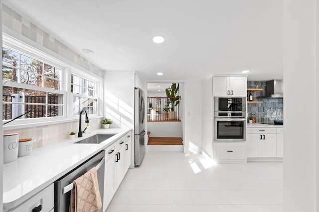 kitchen with sink, tasteful backsplash, white cabinetry, appliances with stainless steel finishes, and wall chimney range hood