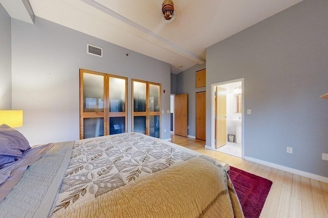 bedroom featuring light wood-style floors, visible vents, vaulted ceiling, and baseboards