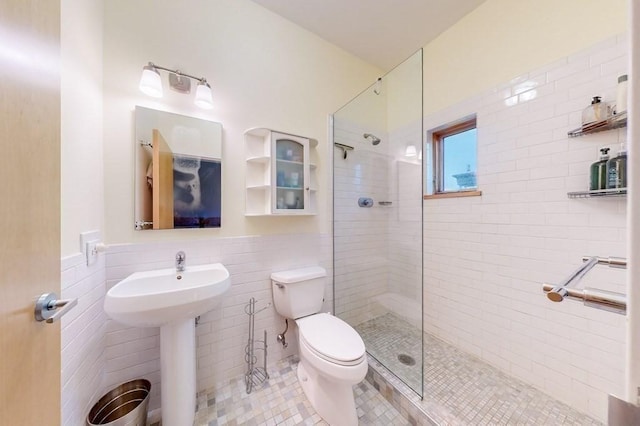 full bathroom featuring toilet, tile patterned flooring, tile walls, and a tile shower