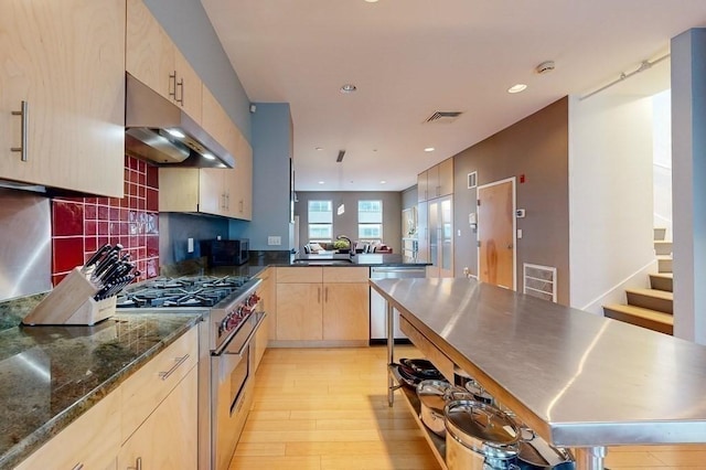 kitchen featuring under cabinet range hood, stainless steel appliances, a sink, light wood-style floors, and light brown cabinetry