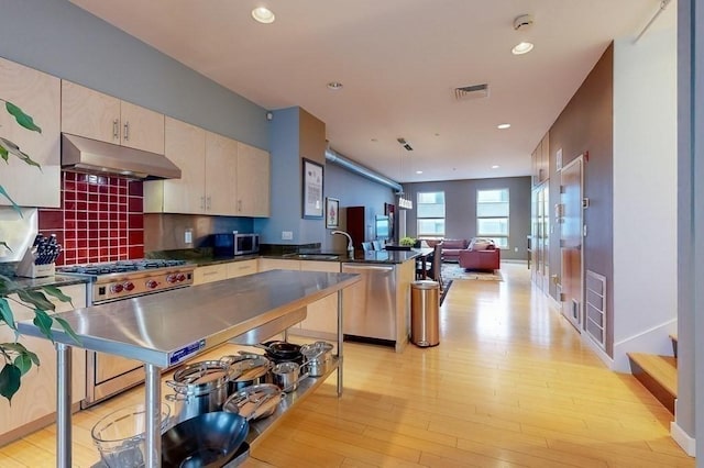 kitchen featuring visible vents, dark countertops, open floor plan, stainless steel appliances, and under cabinet range hood