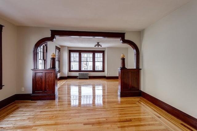 174 Vernon St, Worcester, MA 01610 - unfurnished living room featuring radiator heating unit, light wood finished floors, baseboards, and arched walkways