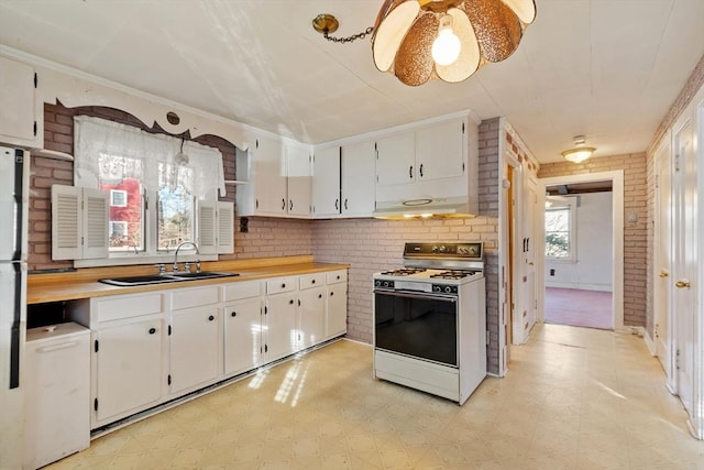 kitchen featuring white cabinets, white appliances, brick wall, and sink