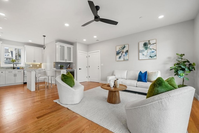 living room featuring ceiling fan, light hardwood / wood-style floors, sink, and wine cooler