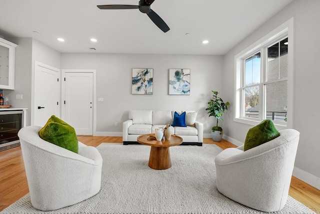 living room featuring ceiling fan, beverage cooler, and light hardwood / wood-style flooring