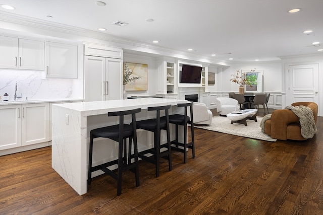 kitchen with sink, a center island, a kitchen breakfast bar, and dark hardwood / wood-style floors