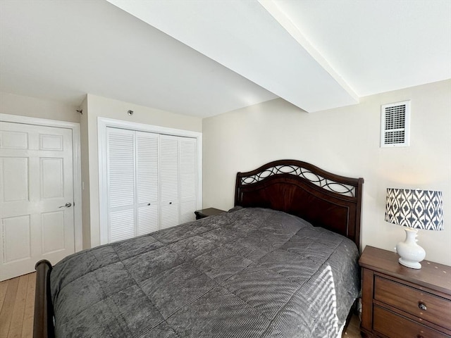 bedroom with a closet, visible vents, and wood finished floors