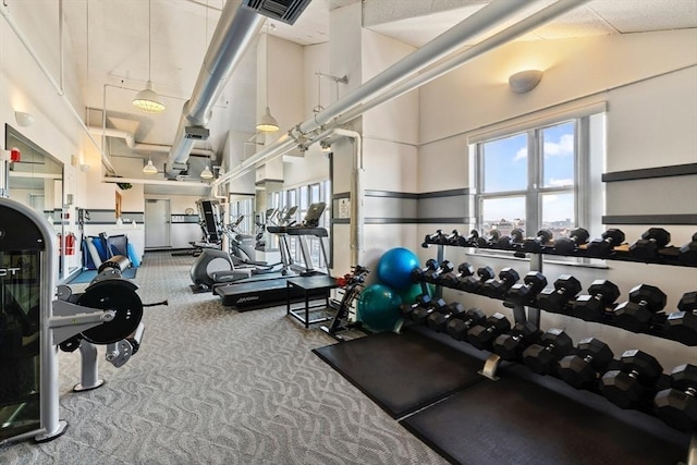 workout area with visible vents, a towering ceiling, and carpet flooring