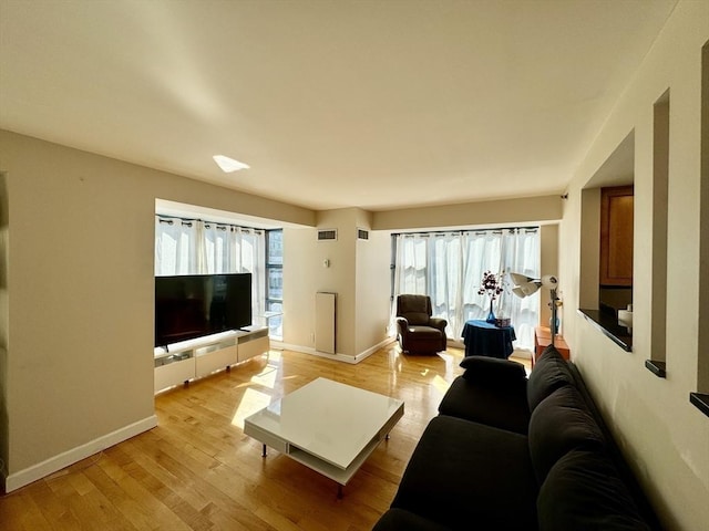 living area with baseboards, visible vents, and light wood-style floors