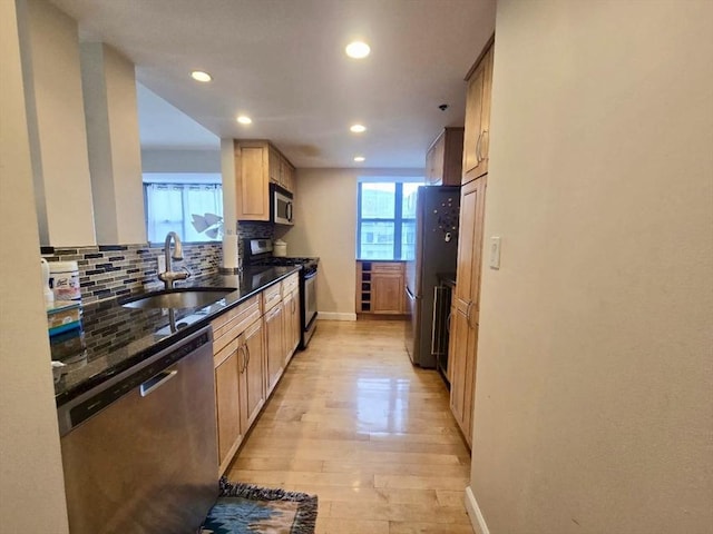 kitchen featuring appliances with stainless steel finishes, a healthy amount of sunlight, a sink, and tasteful backsplash